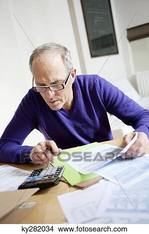 Man using calculator and filling his tax form View Large Photo Image Picture - Man using calculator and filling his tax form. Fotosearch