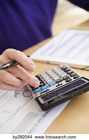 Man using calculator and filling his tax form View Large Photo Image Picture - Man using calculator and filling his tax form. Fotosearch