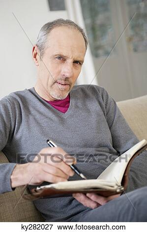 Portrait of a man writing in a personal organizer View Large Photo Image Stock Photo - Portrait of a man writing in a personal organizer. Fotosearch