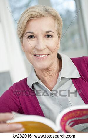 Stock Photograph - Portrait of a woman holding a book and smiling. Fotosearch