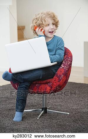 Boy talking on a mobile phone and using a laptop View Large Photo Image Stock Image - Boy talking on a mobile phone and using a laptop. Fotosearch