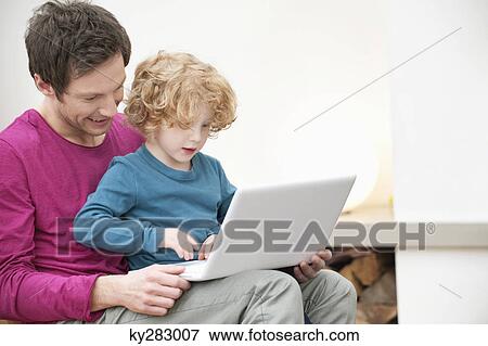 Close-up of a man assisting his son in using a laptop View Large Photo Image Stock Photo - Close-up of a man assisting his son in using a laptop. Fotosearch