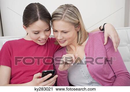 Woman and her daughter reading a text message on a mobile phone View Large Photo Image Stock Image - Woman and her daughter reading a text message on a mobile phone. Fotosearch