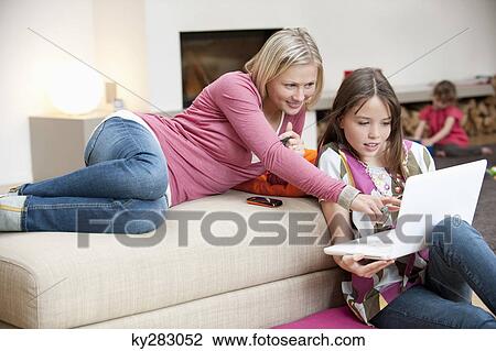 Woman assisting her daughter in using a laptop View Large Photo Image Stock Image - Woman assisting her daughter in using a laptop. Fotosearch