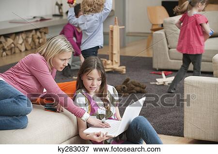 Woman assisting her daughter in using a laptop View Large Photo Image Stock Photo - Woman assisting her daughter in using a laptop. Fotosearch