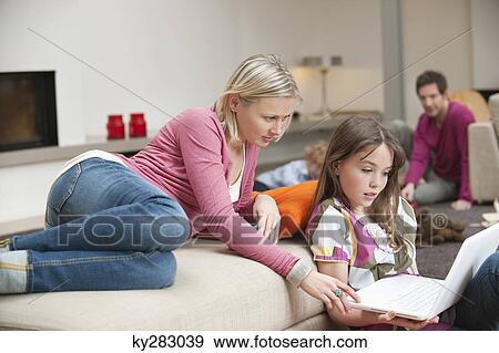 Woman assisting her daughter in using a laptop View Large Photo Image Stock Photo - Woman assisting her daughter in using a laptop. Fotosearch