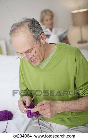 Man knitting with a woman in the background View Large Photo Image Picture - Man knitting with a woman in the background. Fotosearch