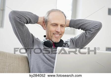 Man looking at a laptop and smiling View Large Photo Image Stock Image - Man looking at a laptop and smiling. Fotosearch