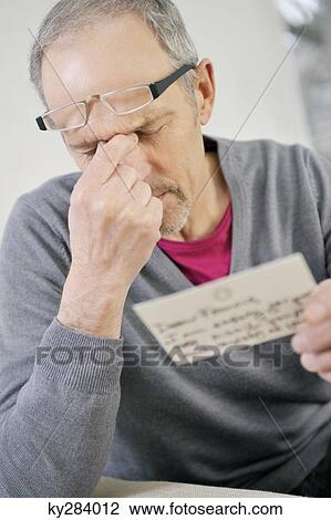 Man looking serious while reading a postcard View Large Photo Image Stock Image - Man looking serious while reading a postcard. Fotosearch