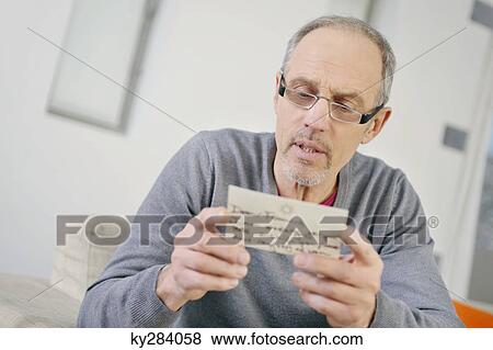 Man looking serious while reading a postcard View Large Photo Image Stock Photo - Man looking serious while reading a postcard. Fotosearch