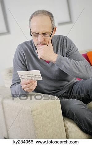 Man looking serious while reading a postcard View Large Photo Image Stock Photograph - Man looking serious while reading a postcard. Fotosearch