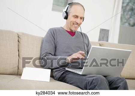 Man using a laptop and listening to music View Large Photo Image Picture - Man using a laptop and listening to music. Fotosearch