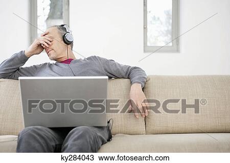 Man using a laptop and listening to music View Large Photo Image Stock Image - Man using a laptop and listening to music. Fotosearch