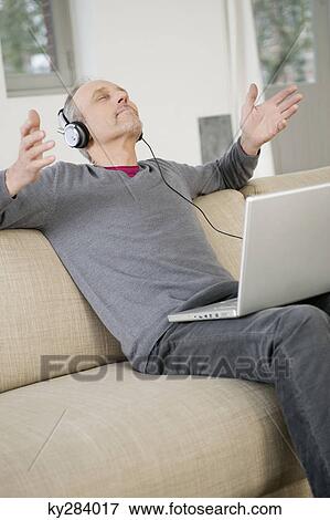 Man using a laptop and listening to music View Large Photo Image Stock Photo - Man using a laptop and listening to music. Fotosearch