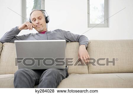 Man using a laptop and listening to music View Large Photo Image Stock Photo - Man using a laptop and listening to music. Fotosearch