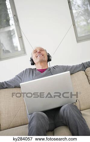 Man using a laptop and listening to music View Large Photo Image Stock Photo - Man using a laptop and listening to music. Fotosearch
