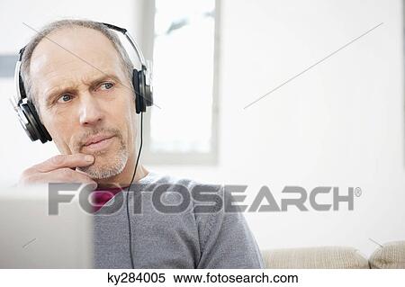 Stock Photography - Man using a laptop and listening to music. Fotosearch