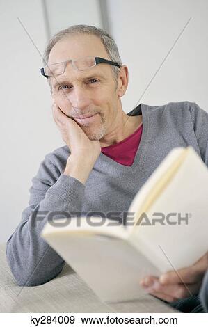 Portrait of a man holding a book and smiling View Large Photo Image Stock Photo - Portrait of a man holding a book and smiling. Fotosearch