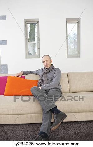 Portrait of a man sitting on a couch View Large Photo Image Stock Photograph - Portrait of a man sitting on a couch. Fotosearch