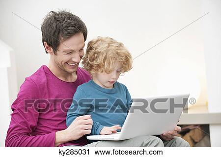 Close-up of a man assisting his son in using a laptop View Large Photo Image Stock Image - Close-up of a man assisting his son in using a laptop. Fotosearch