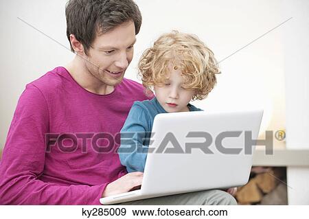 Close-up of a man assisting his son in using a laptop View Large Photo Image Stock Photo - Close-up of a man assisting his son in using a laptop. Fotosearch
