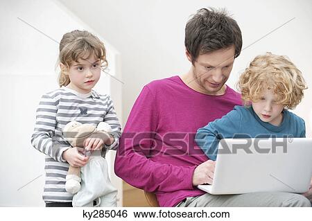 Close-up of a man assisting his son in using a laptop View Large Photo Image Stock Photograph - Close-up of a man assisting his son in using a laptop. Fotosearch