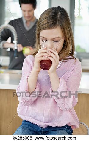 Girl drinking juice with her father standing behind her View Large Photo Image Stock Photo - Girl drinking juice with her father standing behind her. Fotosearch