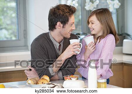Picture - Man drinking coffee with his daughter. Fotosearch
