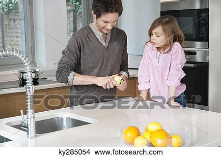 Picture - Man preparing breakfast with his daughter standing with him. Fotosearch