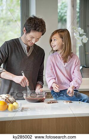 Stock Image - Man stirring a mixture in a bowl with his daughter. Fotosearch