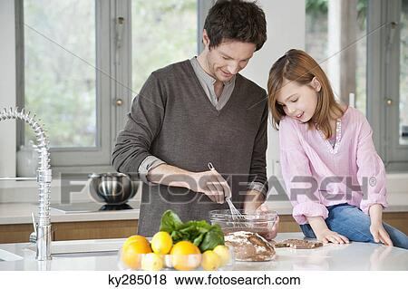 Stock Photo - Man stirring a mixture in a bowl with his daughter. Fotosearch
