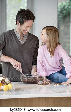 Stock Photo - Man stirring a mixture in a bowl with his daughter. Fotosearch