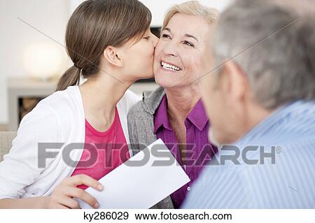 Girl kissing her grandmother with her grandfather sitting beside them View Large Photo Image Stock Photo - Girl kissing her grandmother with her grandfather sitting beside them. Fotosearch