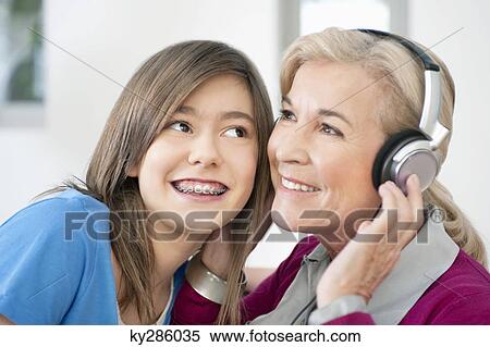 Woman with her granddaughter listening to headphones View Large Photo Image Stock Photography - Woman with her granddaughter listening to headphones. Fotosearch