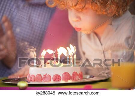 Stock Photography - Boy blowing out candles on his birthday cake. Fotosearch