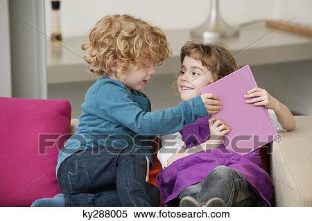 Stock Photography - Boy sitting on a couch with his sister. Fotosearch