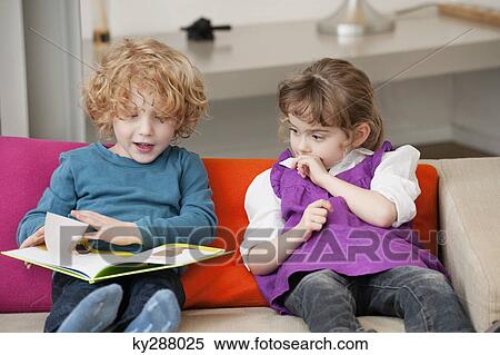 Stock Photography - Boy sitting with his sister and reading a book. Fotosearch