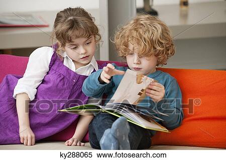 Boy sitting with his sister and reading a book View Large Photo Image Stock Photography - Boy sitting with his sister and reading a book. Fotosearch