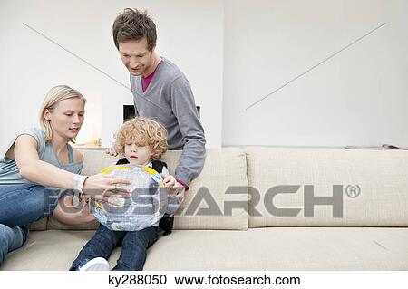 Parents in a living room with their son holding a globe View Large Photo Image Stock Image - Parents in a living room with their son holding a globe. Fotosearch