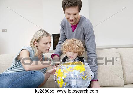 Parents in a living room with their son holding a globe View Large Photo Image Stock Photography - Parents in a living room with their son holding a globe. Fotosearch