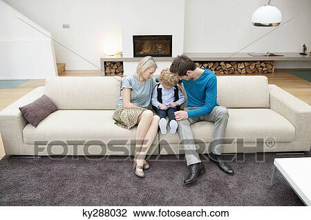 Parents sitting on a couch with their son View Large Photo Image Stock Image - Parents sitting on a couch with their son. Fotosearch