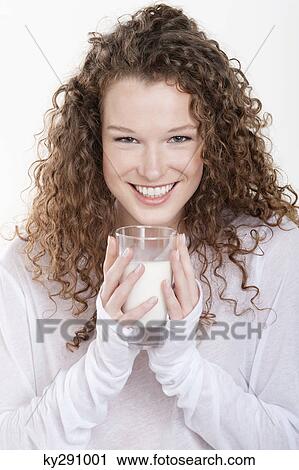 Stock Image - Portrait of a woman holding a glass of milk and smiling. Fotosearch