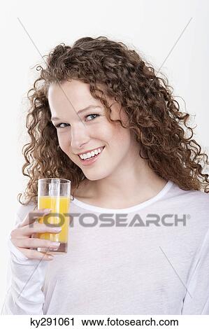 Stock Image - Portrait of a woman holding a glass of orange juice. Fotosearch