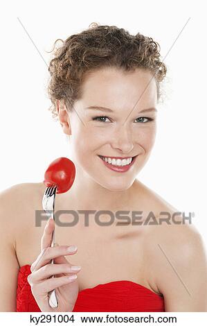 Portrait of a woman holding a tomato on a fork View Large Photo Image Picture - Portrait of a woman holding a tomato on a fork. Fotosearch