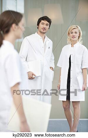 Stock Image - Male doctor standing with two female doctors. Fotosearch