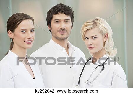 Stock Image - Male doctor standing with two female doctors. Fotosearch