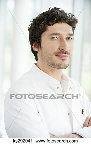 Stock Image - Portrait of a doctor standing with his arms crossed. Fotosearch
