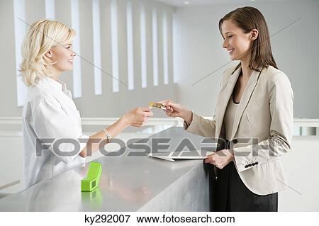 Stock Photo - Woman making payment with credit card in a hospital. Fotosearch