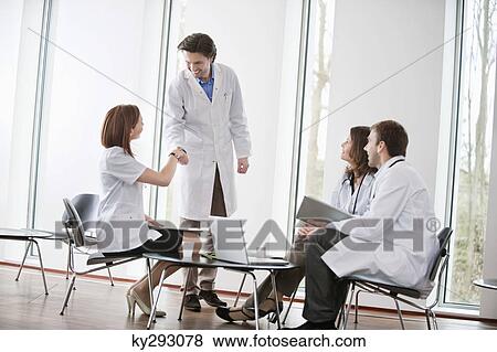 Doctor shaking hands with a female doctor View Large Photo Image Stock Photo - Doctor shaking hands with a female doctor. Fotosearch