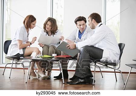 Doctors sitting on chairs discussing medical reports View Large Photo Image Stock Photography - Doctors sitting on chairs discussing medical reports. Fotosearch